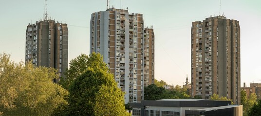 Tall residential buildings in the settlement Podbara in Novi Sad, trees around, sky background