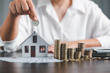 Saving investment home with loan finance money business concept. Investment banking finance for residential real estate business. Stack coins with model house for investment loans.Cash for taxes.