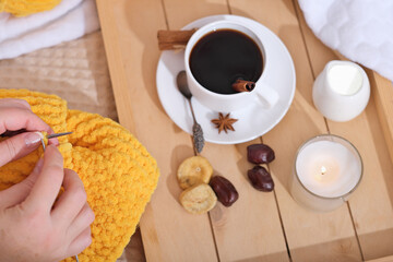 Woman knitting with a cup of cinnamon coffee, snacks and candle. cozy home hobby, autumn and winter leisure. self time, concentration and inner peace. top view