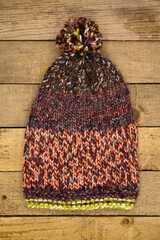 Handmade wool knitted winter brown hat on wooden background