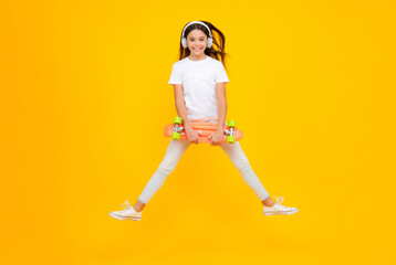 Fototapeta na wymiar Teenagers lifestyle, casual youth culture. Teen girl with skateboard over isolated studio background. Cool modern teenager in stylish clothes. Happy teenager portrait. Smiling girl. Jump and run.