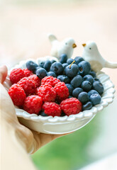 Fresh berries in a white vase in the hand. Delicious, quick and healthy snack in the morning or evening