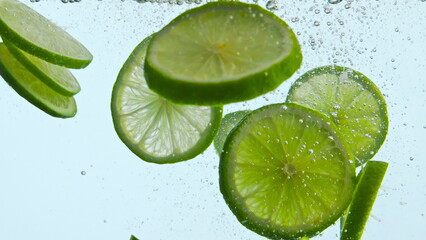Fresh green lime underwater on white background close up. Citrus floating water 