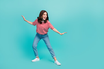 Full length photo of pretty sweet lady wear striped t-shirt having fun riding surf looking empty space isolated turquoise color background