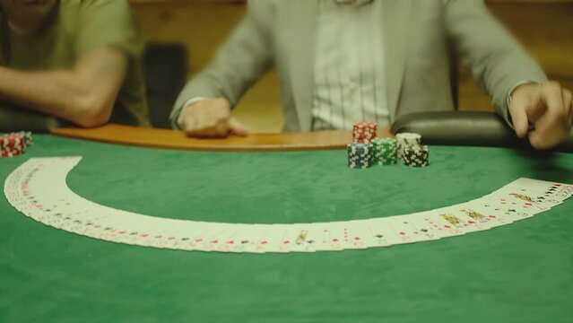 Casino: Dealer man shuffles the playing cards and performing trick with cards on green colored table. Concept of poker , black jack . Shot on ARRI ALEXA Cinema Camera in slow motion , close up . 