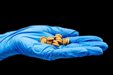 Obraz premium Medical pills on isolated black background with reflection in hand