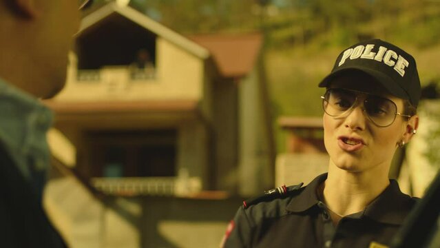 Beautiful woman in police uniform or female cop checking documents of man sitting in car on city street . Serious policeman checking male drivers license after exceeding speed limit .  Giving honor .