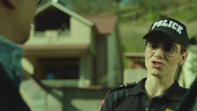 Beautiful woman in police uniform or female cop checking documents of man sitting in car on city street . Serious policeman checking male drivers license after exceeding speed limit .  Giving honor .
