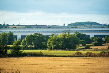 Fototapeta na wymiar new built distribution warehouse building with farm fields in foreground in england uk