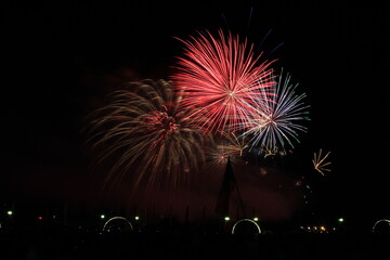Fototapeta na wymiar Multicolored fireworks in the dark sky, city day celebration.