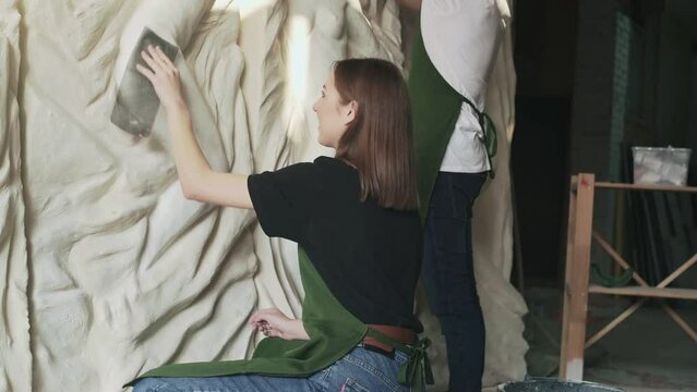 Two sculptor works with plaster structural composition on the wall of women