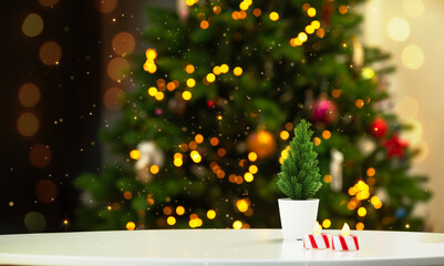 Empty table with small fir and candles in front of blurred shining lights of christmas tree. New...