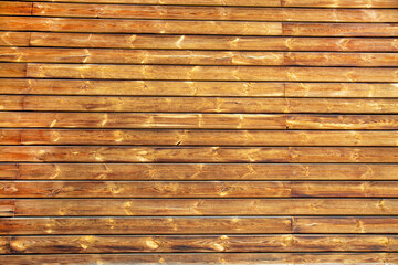 The background of the wall is made of planed wooden boards of brown color with a beautiful pattern of the structure. Design backgrounds textures construction.