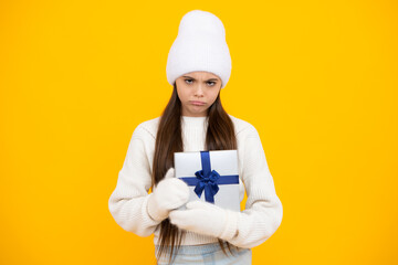 Teenager child in winter wear holding gift boxes celebrating happy New Year or Christmas. Winter kids holiday. Angry teenager girl, upset and unhappy negative emotion.