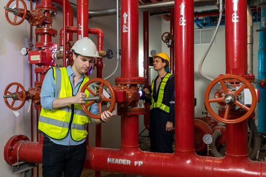 Engineer Or Technician Work Checking Fire Suppression System And Fire Equipment. Engineer Check Red Generator Pump For Water Sprinkler Piping And Fire Alarm Control System