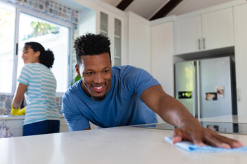 Happy african american couple cleaning countertop together in kitchen - Powered by Adobe
