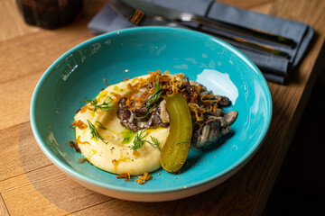 mashed potatoes with grilled meat on a white plate in a restaurant