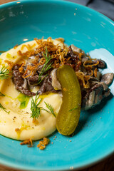 mashed potatoes with grilled meat on a white plate in a restaurant