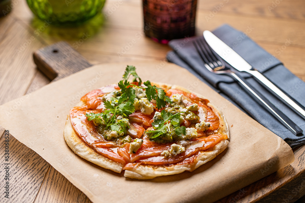 Wall mural pizza with salmon on the table in the restaurant