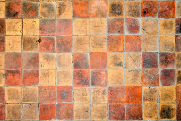 Orange brown purple old shabby worn out floor tiles with damages cracks dirt caverns potholes and...