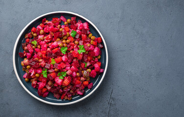 Vegetable salad with beetroot, pickled cucumbers and peas on a dark background. Traditional vinaigrette. Top view, copy space.