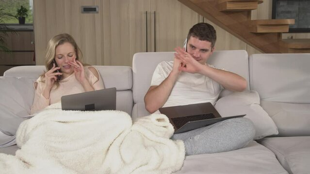 CLOSE UP: Young couple distracting each other while trying to get their work done. Gentle arousal of irritation between partners trying to work at home. Twosome working form home during quarantine.