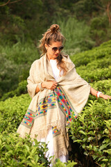 Portrait of adult female in in white clothe, standing in tea plant. Happy stylish woman in casual traditional wear and sunglasses at tea plantation background landscape in Sri Lanka. Copy text space