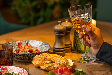a glass of white wine in a man's hand against the background of a laid table in a restaurant