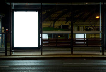 Outdoor advertising billboard at tramway stop at nighttime in the city.