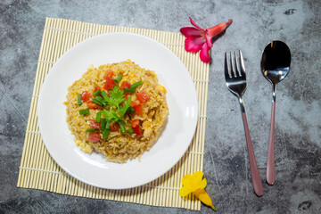 Mom cooks dinner, fried rice with eggs, sprinkled vegetables and tomato.