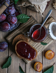 Homemade plum jam and fresh berries on a wooden background. Homemade preserving concept. Summer seasonal berry jams