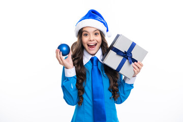 Santa child girl. New Year or Christmas holiday gift. Excited face. Child with gift present box on isolated studio background. Gifting for kids birthday. Amazed expression, cheerful and glad.