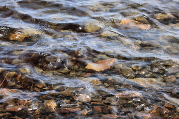 Stones under clear water with ripples
