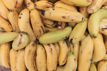 Pile of yellow bananas in woven bamboo called tampah on the paving floor photographed from the top corner
