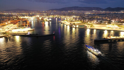 Obraz premium Aerial drone night shot of passenger ferry arriving to famous passenger port of Piraeus one of the largest in Europe, Attica, Greece