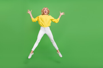 Photo of shiny excited lady dressed yellow pullover jumping high like star empty space isolated green color background