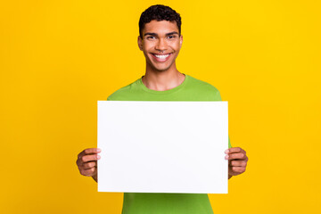 Photo of young attractive handsome smiling guy hold white paper billboard recommend advertisement...