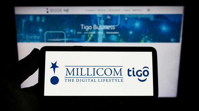 Stuttgart, Germany - 10-03-2022: Person holding smartphone with logo of company Millicom International Cellular S.A. on screen in front of website. Focus on phone display.