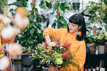 Woman arranges bouquet from flowers in florist shop