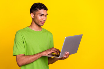 Photo of young handsome confident professional user hold new laptop concentrated marketology isolated on yellow color background