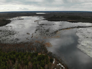Spring lake with ice in forest. Aerial drone view. Flying over. Drone is moving. High quality photo