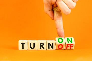 Turn on or off symbol. Concept words Turn off and Turn on on wooden cubes. Beautiful orange table orange background. Businessman hand. Business Turn on or off concept. Copy space.