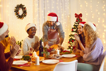 Happy diverse friends sit at table eating delicious Christmas food celebrate winter holidays...