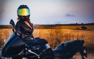 sensual biker woman dressed in black preparing to ride her motorcycle near jerez de la frontera,...