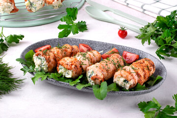 Chicken rolls stuffed with lettuce, egg, cheese, cucumber and sour cream served on the gray plate. Hot appetizing meal
