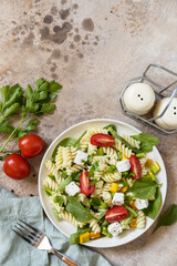 Italian food - Salad with gluten free pasta, spinach, tomatoes, beans and feta cheese on a stone table. Healthy food, vegetarian appetizer. View from above. Copy space.