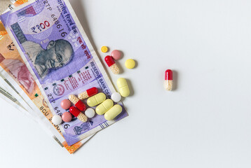Assorted capsules and tablets placed with Indian rupee currency notes. Concept for cheap generic medicine or expenses for medical treatment.