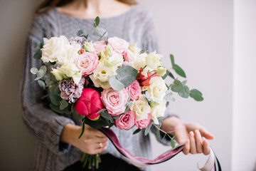 Very nice young woman holding big and beautiful flower bouquet of fresh peony, roses, carnations, eustoma, eucalyptus in tender pink and white colors, close up view  - 538087536