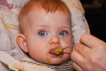 a small child eats from a spoon. got dirty with dirt. High quality photo