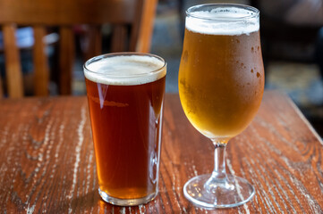 Pint glasses of british ale and lager beer served in old vintage English pub
